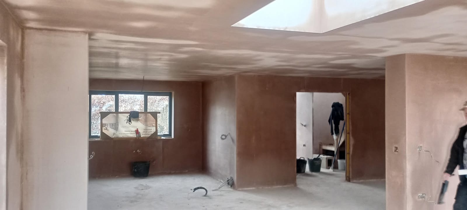 An open-plan room with a roof light, walls and ceiling newly plastered