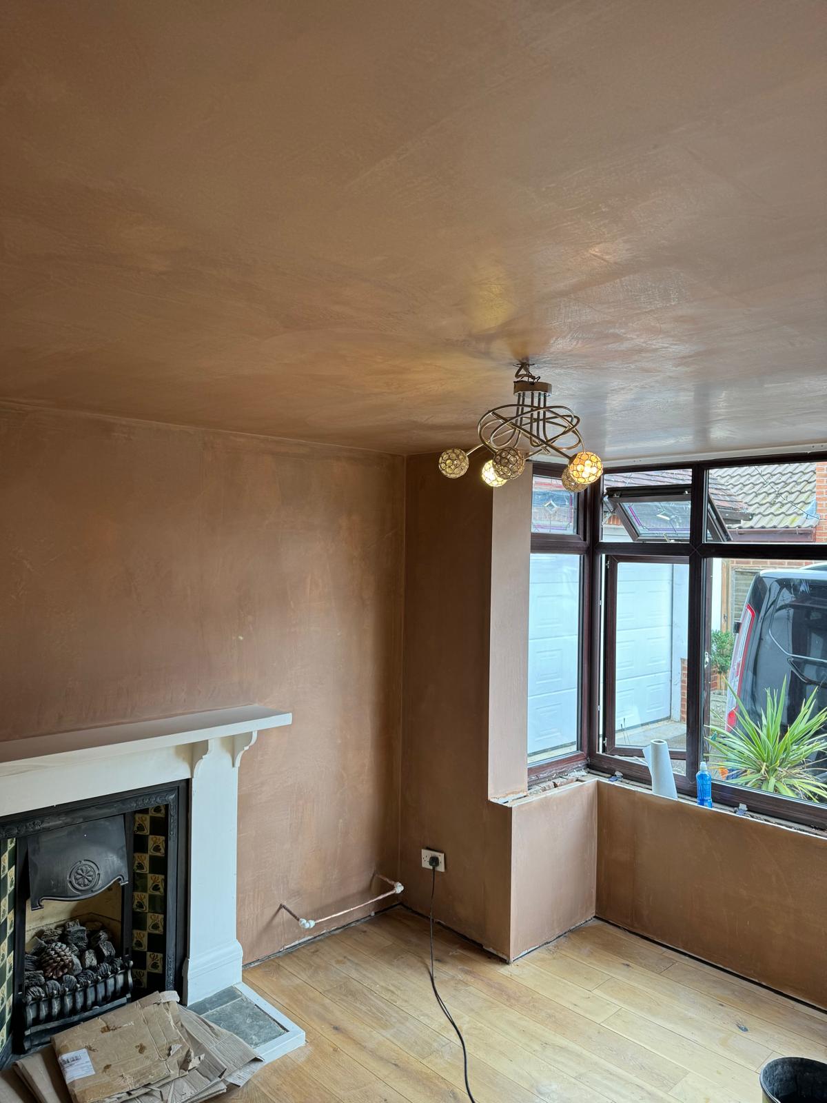 A living room with a fireplace, walls and ceiling freshly plastered
