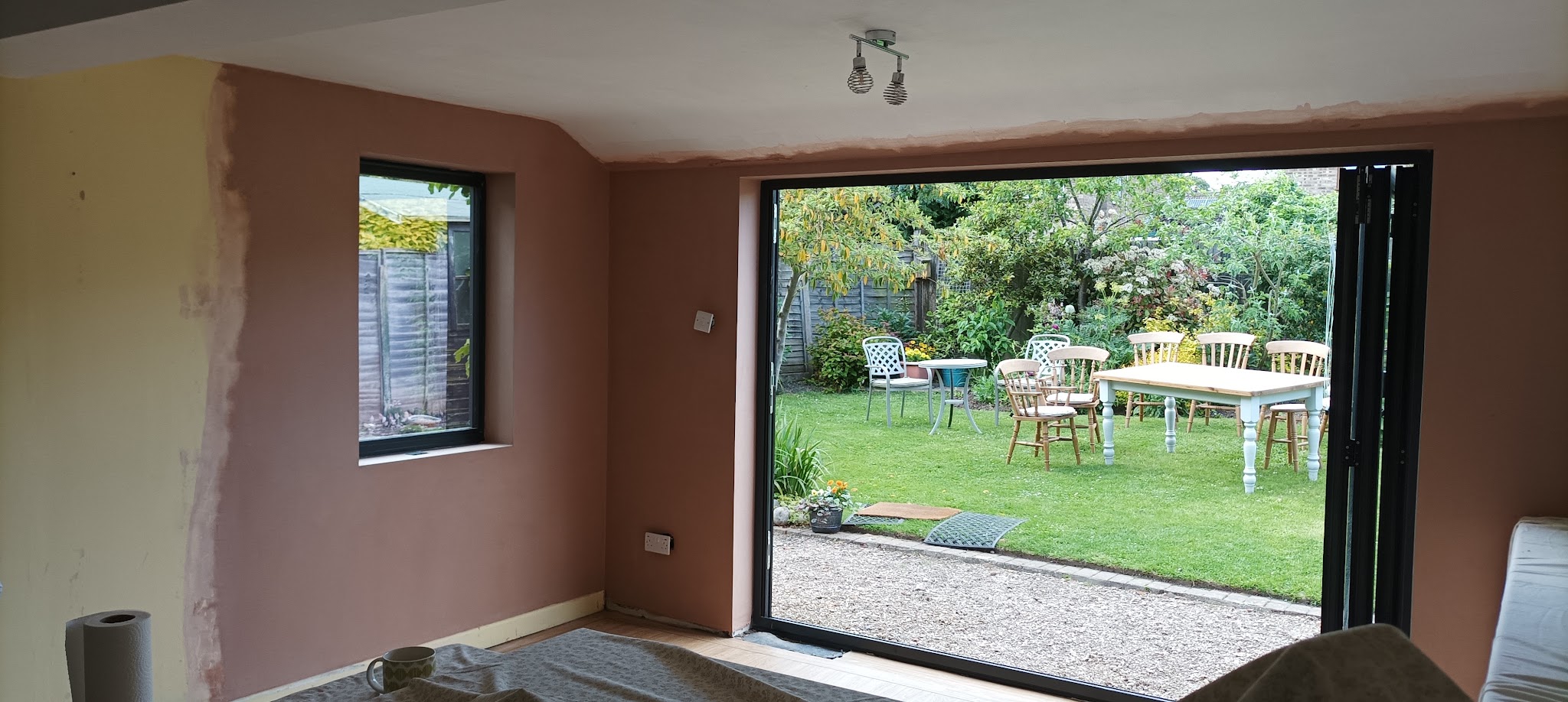 An extension room with bifold doors open to the garden, freshly plastered